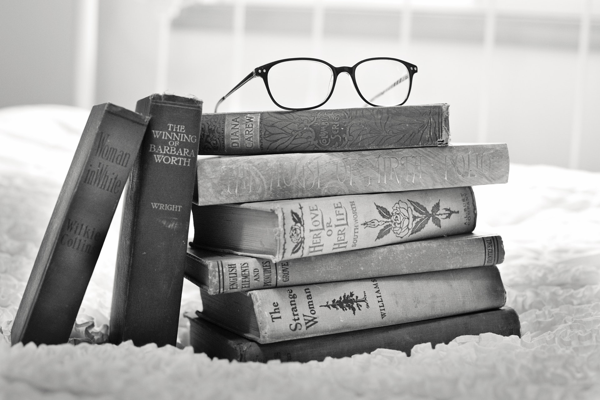 A pair of glasses sit on top of a stack of 6 books
